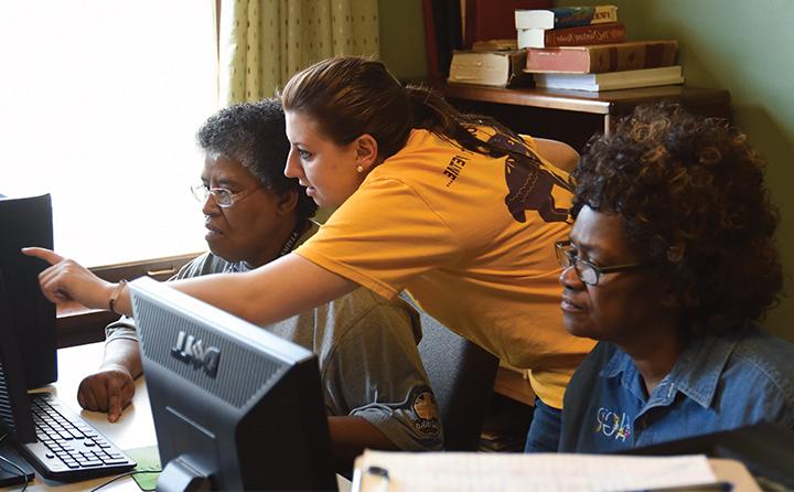 Photo of student helping two women on computers